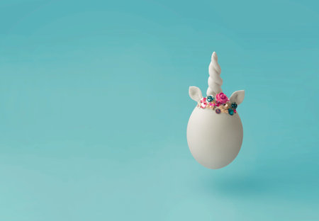 Single white egg, with unicorn decoration; Creative minimal Easter background with copy spaceの写真素材