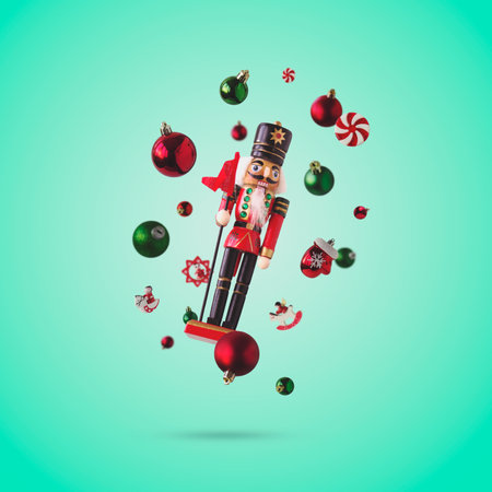 Nutcracker and Christmas baubles on green background, levitating. Christmas and New Year creative...
