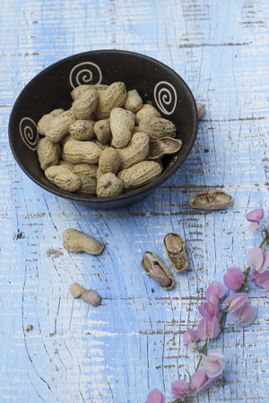 Unpeeled peanuts in bowl on wooden background closeupの写真素材
