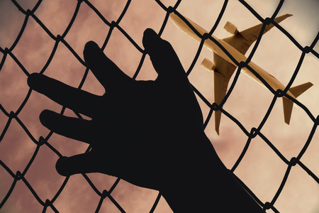 Hands of the man arrested mesh fence Watched the plane.の写真素材