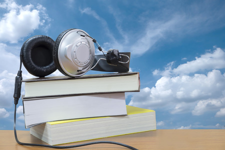 Headphones and book on sky backgroundの写真素材