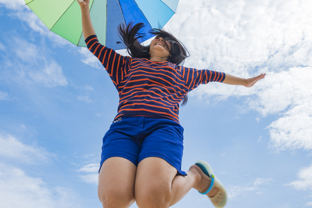 Young woman holding colorful umbrella on the beach in summer . Summer Vacation Concept.の写真素材