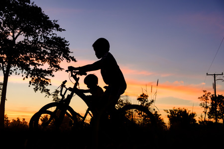 silhouette of little boy riding bike at sunset, kids sport and active lifestyleの写真素材