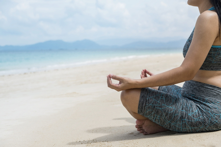 Young beautiful healthy woman making meditation on the beachの写真素材
