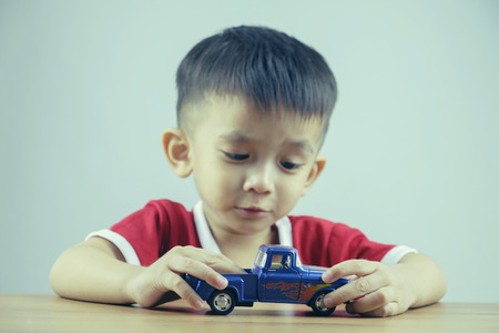 Little boy playing with toy car at home. Filtered image processed vintage effect.