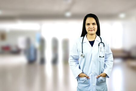 young woman doctor with white coat standing in hospitalの写真素材