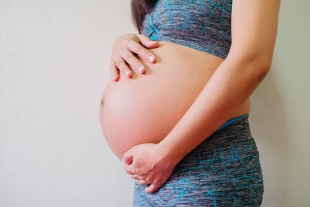 Pregnant woman touching belly. Portrait of the young happy smiling pregnant woman