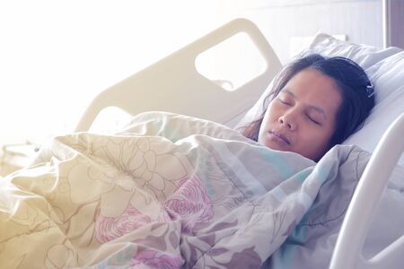 Patient Asian woman sleeping under blanket on sick bed at the hospital. Patient and hospital concept.の写真素材