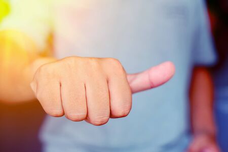 Young man giving thumb up as sign of success. Focus at hands.