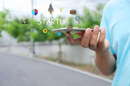 Man is using mobile phone. Startup business concept with young man holding his smartphone outside in the park.の写真素材