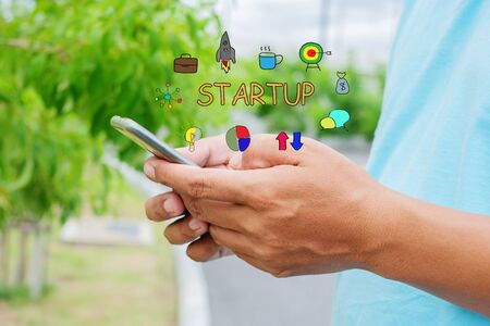 Man is using mobile phone. Startup business concept with young man holding his smartphone outside in the park.の写真素材