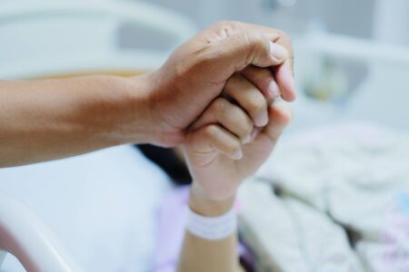 Close up focus on the Shake hands of a patient sick encourage encouragement on the bed in hospital ward. Healthcare concept.の写真素材
