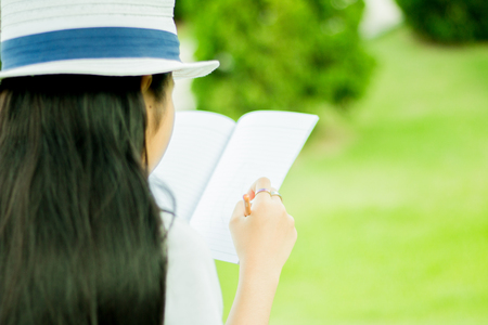 young woman sitting on the grass and reading the bookの写真素材