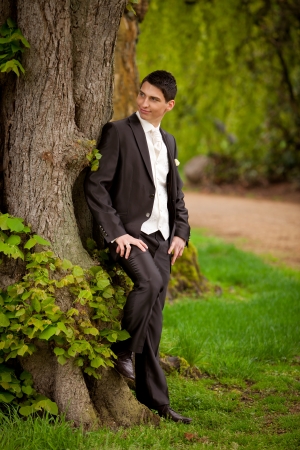 groom is standing at the tree and waiting for his bride while looking where she is の写真素材