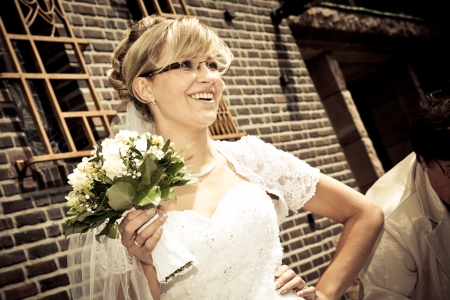 Bride with eyeglasses and sepia color is standing and holding a bunch bouquet of yellow rosesの写真素材