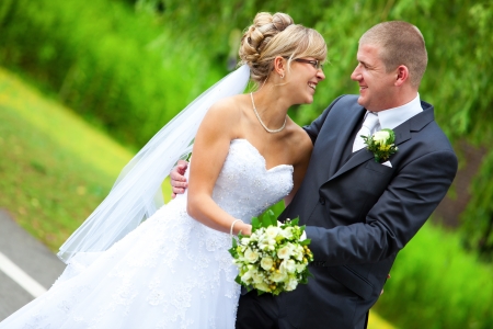 BRIDE AND GROOM LAUGHING and looking to each other while holding the yellow roses bouquetの写真素材