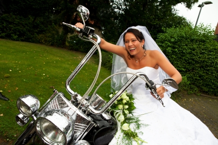Funny bride well know as bride chick is laughing and sitting on a bike after her wedding ceremony  の写真素材