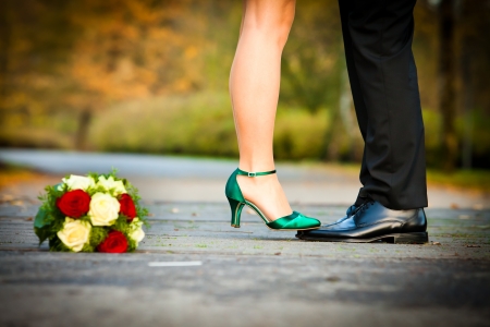 bride is standing with green bridal shoes on grooms black glossy leather shoesの写真素材