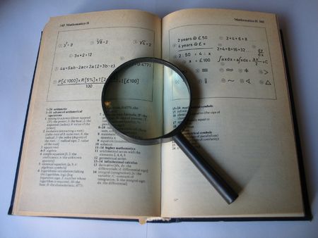 Magnifying glass on open grey book on table in libraryの写真素材
