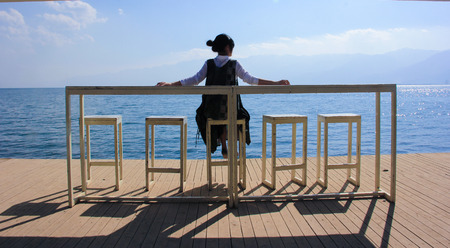 A woman sitting beside the seaの写真素材