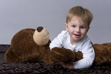 Portrait of happy baby boy playing with his teddy bear の写真素材
