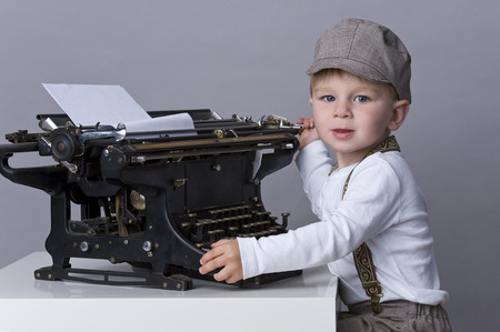 Portrait of happy baby boy playing with old typewriter の写真素材