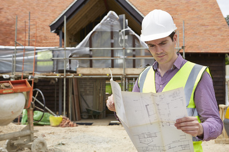 Architect On Building Site Looking At Plans For Houseの写真素材