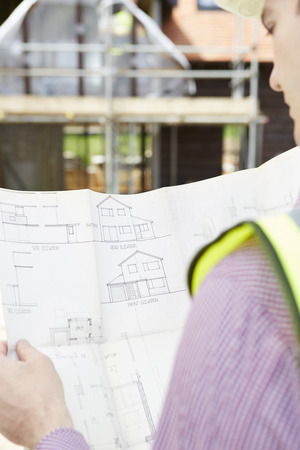 Architect On Building Site Looking At Plans For Houseの写真素材