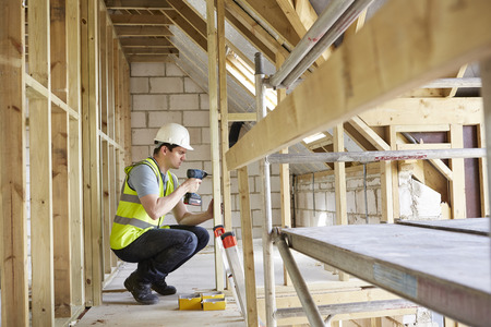 Construction Worker Using Drill On House Build