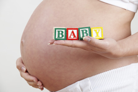 Pregnant Woman Holding Wooden Blocks Spelling Babyの写真素材