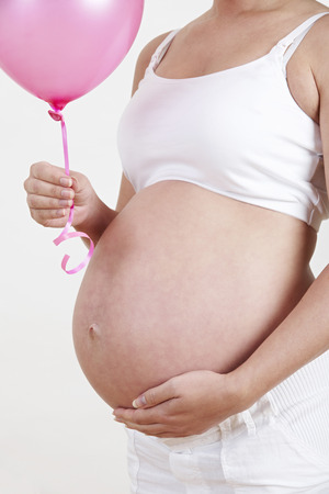 Close Up Of Pregnant Woman Holding Pink Balloonの写真素材