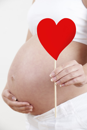 Close Up Of Pregnant Woman Holding Heart Shape On Stickの写真素材