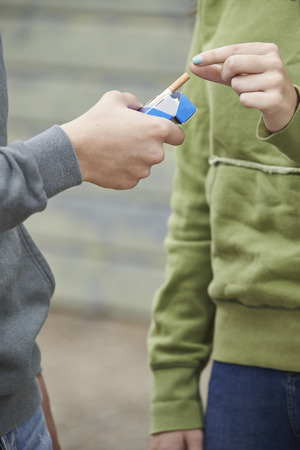 Close Up Of Teenager Boy Offering Girl Cigarette の写真素材