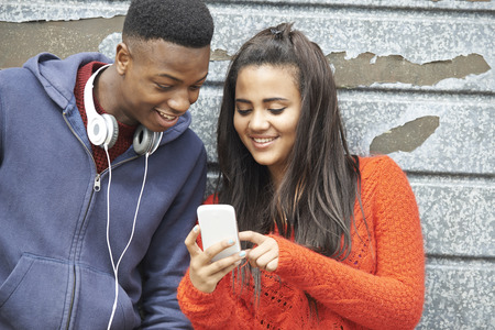 Teenager Couple Sharing Text Message On Mobile Phoneの写真素材