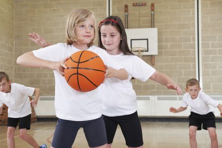 Elementary School Pupils Playing Basketball In Gymの写真素材