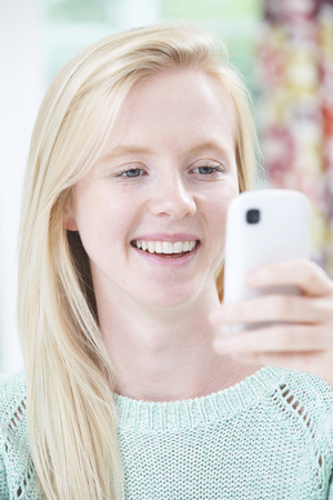 Smiling Young Woman Reading Text Messageの写真素材