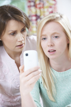 Mother Comforting Daughter Being Bullied By Text Messageの写真素材