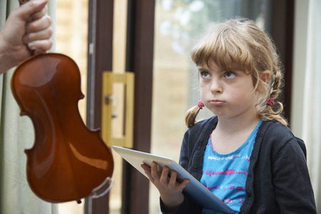 Young Girl Would Rather Play On Digital Tablet Than Practise Violinの写真素材