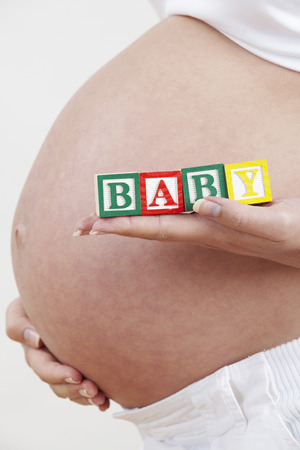 Close Up Of Pregnant Woman Holding Blocks Spelling Babyの写真素材