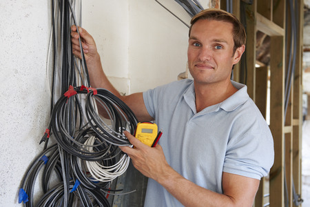 Electrician Fitting Wiring On Construction Site