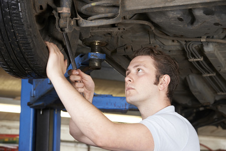 Mechanic Working On Wheel Underneath Carの写真素材