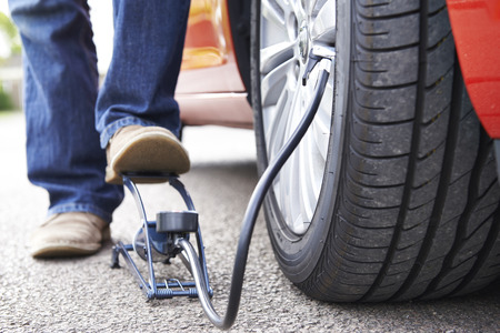 Close Up Of Man Inflating Car Tyre With Foot Pumpの写真素材