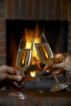 Couple With Glass Of Champagne Relaxing By Fireの写真素材