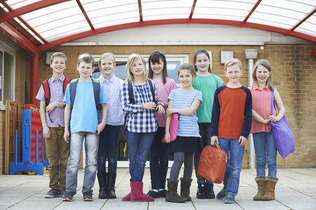 Portrait Of School Pupils Outside Classroom Carrying Bags