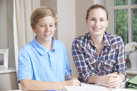 Female Home Tutor Helping Boy With Studiesの写真素材