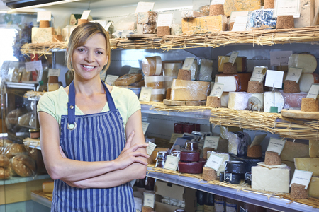 Owner Of Delicatessen Standing Next To Cheese Displayの写真素材