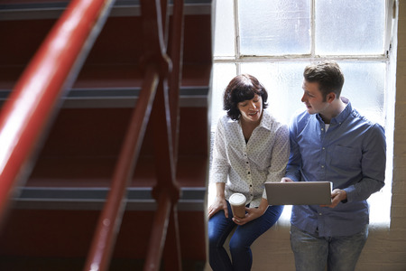 Two Businesspeople Having Informal Meeting On Office Stairsの写真素材