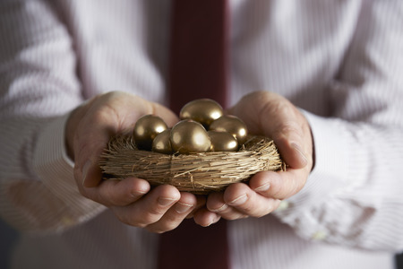 Businessman Holding Nest Full Of Golden Eggsの写真素材