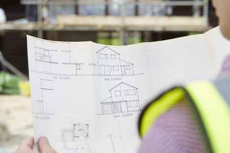 Architect On Building Site Looking At Plans For Houseの写真素材