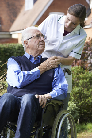 Carer Pushing Senior Man In Wheelchairの写真素材